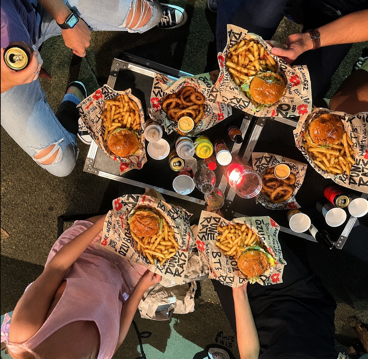 Burgers and fries on a flight-case table at night, seen from above